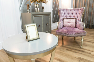 Beautiful luxury house interiour with quilted violet armchair on backfront and white round table in foreground.