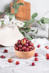 Wooden bowl with fresh sweet gooseberries on light background