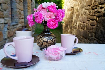 pink roses in the vase, pink mugs with balck tea on the table