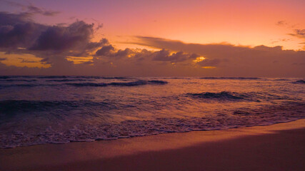 Naklejka na ściany i meble Small waves roll towards a tropical island on a sunny evening.