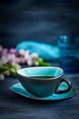 Black coffee and pink flowers on a black background, copy space