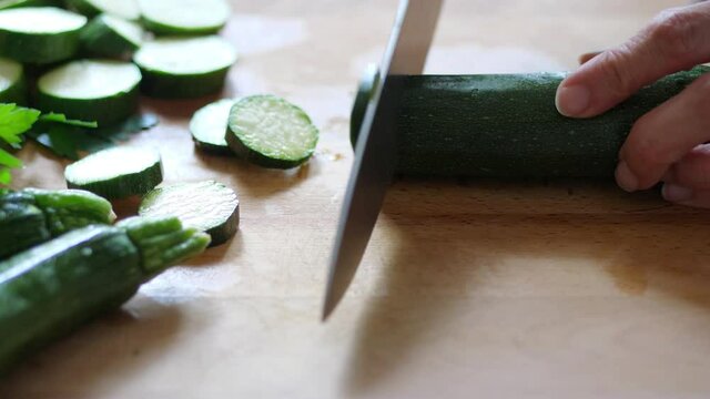 woman cuts zucchini on a wooden cutting board in the kitchen