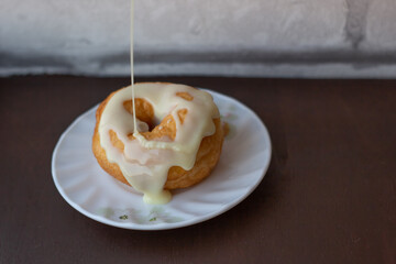 Big juicy donut being poured on with condensed milk
