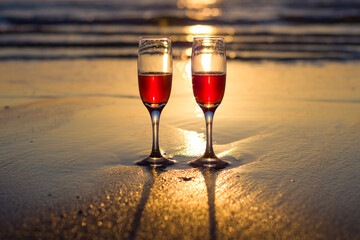 glasses of red wine on the beach in the sunshine , sunset over the sea