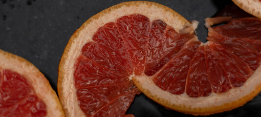 Naklejka na ściany i meble Grapefruit close up on black stone background