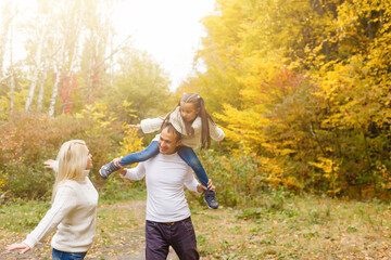 family, childhood, season and people concept - happy family in autumn park
