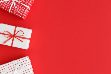 Red and white christmas gifts on a red background. Flat lay with blank copy space.