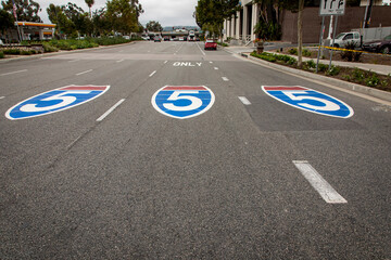 Three signs for the interstate 5 freeway painted on the pavement shot from the driver’s perspective