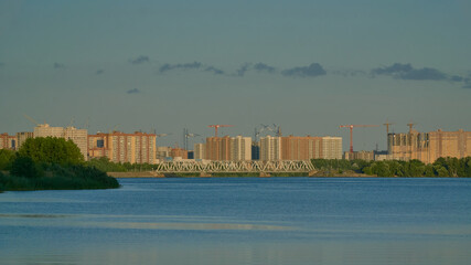 Naklejka premium View of residential buildings in golden light on the Voronezh reservoir from the right bank in summer