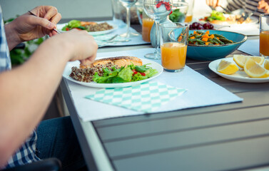 Close up photo of hands man eating salad, quinoa and fish on terrace