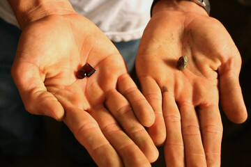 Mãos de trabalhador com pedras, lapidada e bruta.