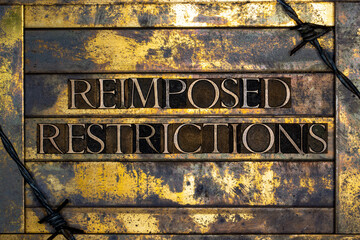 Reimposed Restrictions text formed with real authentic typeset letters on vintage textured silver grunge copper and gold background