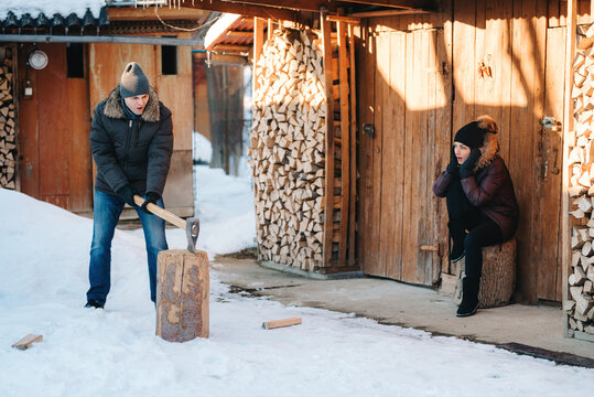 Guy In Winter Clothes Chopping Wood In The Yard