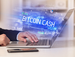 Closeup of businessman hands working on laptop with BITCOIN CASH inscription, succesfull business concept