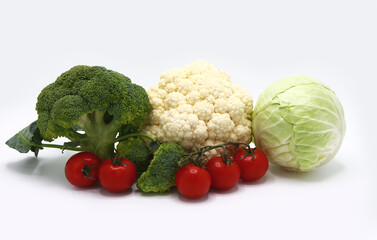 Head of cabbage, inflorescences of broccoli and cauliflower and red ripe tomatoes on a light background. Natural product. Natural hue. Close-up.