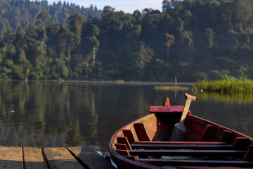 wooden boat leaning against the lake