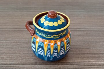 Close up cute pot with colorful painting, blue orange yellow clay jar with handle, traditional bulgarian decoration souvenir. Pottery, earthenware, classic hand crafted activity. White background. 