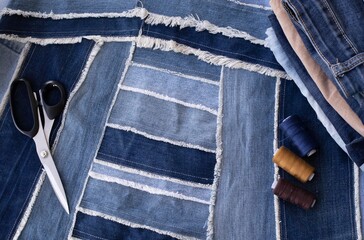 Old jeans ready to upcycling and pattern, made from old jeans pieces, threads and scissors. Concept of things reuse and natural resources preserving.