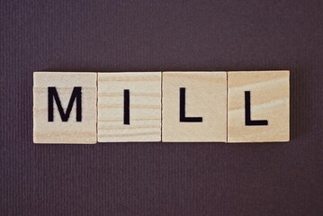 gray word mill made of wooden square letters on brown background