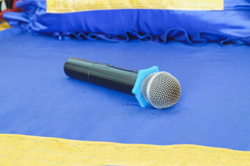 Old black microphone on color table background.