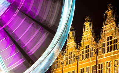 Beautiful view of the Ferris wheel at night. Night illumination of the high Ferris wheel. A long exposition against the background of an old building.