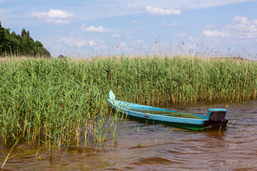 A wooden boat of emerald color sunken after rain in water