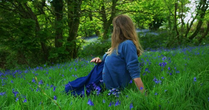Pregnant woman sitting in a meadow of bluebells