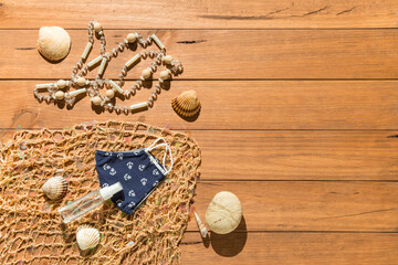 Beach objects, face mask and hydro alcoholic gel on wooden boards.
