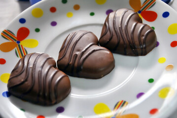 three heart shaped chocolate cookies on colorful round plate