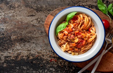 Pasta Bolognese. Tagliatelle with homemade bolognese sauce of minced meat, tomatoes, celery, carrots and spices in a bowl on a black background, top view. Italian Cuisine. Free space for text