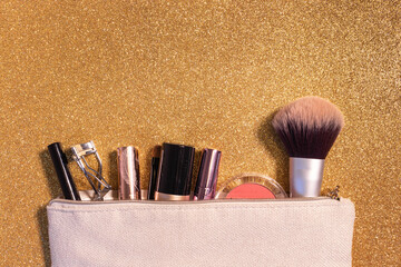 makeup case containing brushes, lipsticks, foundation and tools, gold glitter background