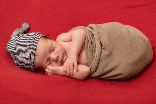 Boy Newborn Sleeping, Wrapped In Red Blanket With Copy Space