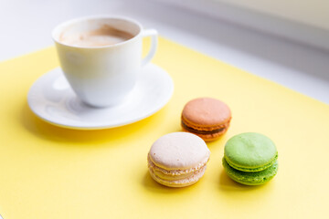 Set of colorful macaroons and coffee.Pastries, confectionery and coffee cup with splash. cookies, macaroons and coffee cupon yellow background. Patisserie shop. good morning card. Copy space