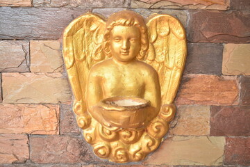 Golden angel holding holy water on the wall
