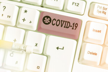 Conceptual hand writing showing Covid19. Concept meaning mild to severe respiratory illness that is caused by a coronavirus White pc keyboard with note paper above white key copy space