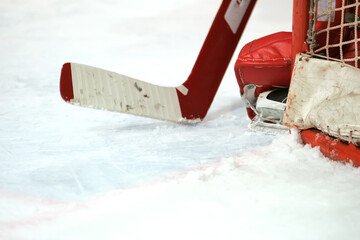 Closeup of goalie's ice hockey stick and skates against white ice