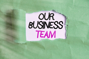 Word writing text Our Business Team. Business photo showcasing meeting and brainstorming, strategic partnership, crowdfunding, success Rolled ripped torn cardboard placed above a wooden classic table