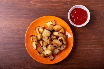 fried potato chips and ketchup on the brown wooden background