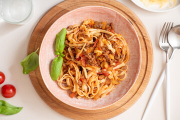 Spaghetti bolognese. Pasta with homemade bolognese sauce of meat, tomatoes, celery, carrots and spices in a bowl on a white served table top view. Italian Cuisine.