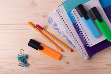 various pens and a pile of notebooks on the wooden backgrounds