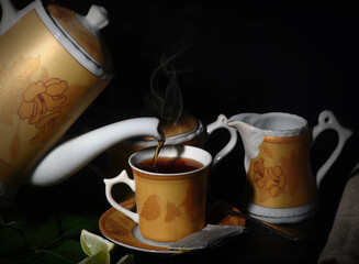 Pouring Ceylon Black Tea from  kettle into a tea cup isolated on Black background