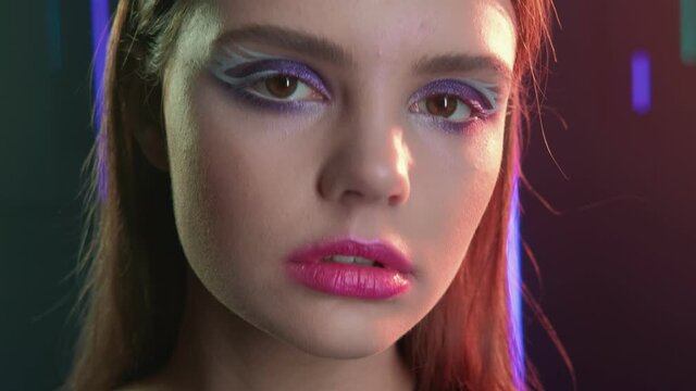 Fashion girl portrait. Festive makeup. Woman with purple eyeshadow pink lips in neon lights.