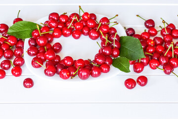 ripe cherries on a white plate and on the table close-up. harvest of ripe cherry berries close-up.