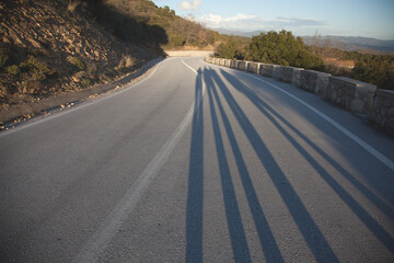 winding road in the mountains, long shadows on the road