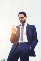 Half length portrait of handsome businessman reading text message on his smartphone