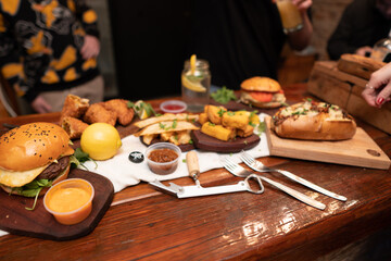 Dinner table with baked potatoes,burgers, sauces, beer and wine