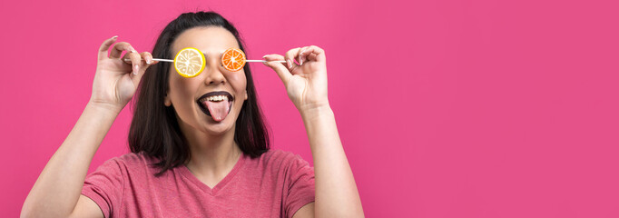 Portrait of lovely sweet beautiful cheerful woman with straight brown hair holding a lollipop near the eyes.