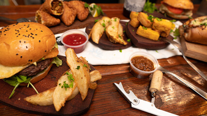 Dinner table with baked potatoes,burgers, sauces, beer and wine