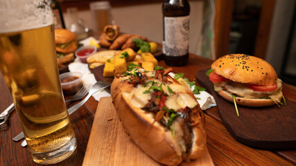 Dinner table with baked potatoes,burgers, sauces, beer and wine