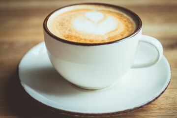 Cappuccino, cup, white, table, cafe, home. A beautiful background with a white cup of cappuccino on the wooden table. Close up.